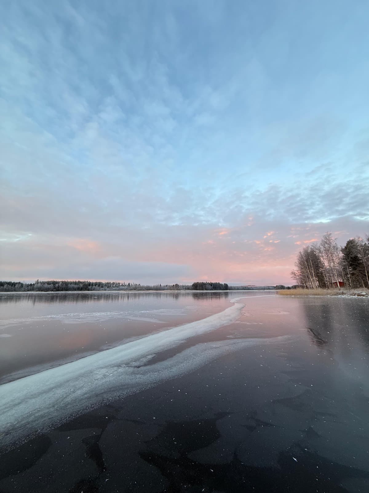 Jäätyvä Saimaa auringonlaskussa, jäärailo ja rantametsä
